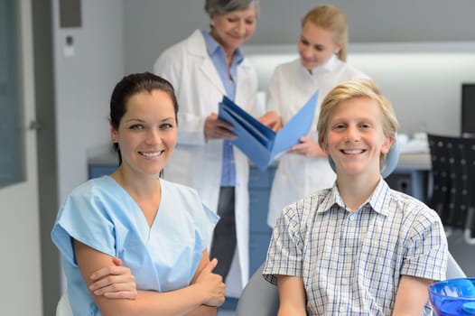 Dental team at stomatology clinic with teenager patient boy smiling
