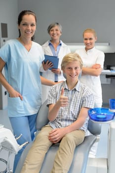Professional dentist team with teenager boy patient thumbup dental surgery