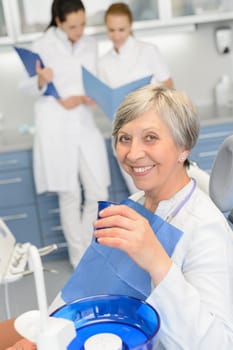 Elderly woman patient dentist team sitting chair at dental surgery