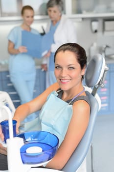 Woman patient sitting chair dental surgery checkup professional dentist team background