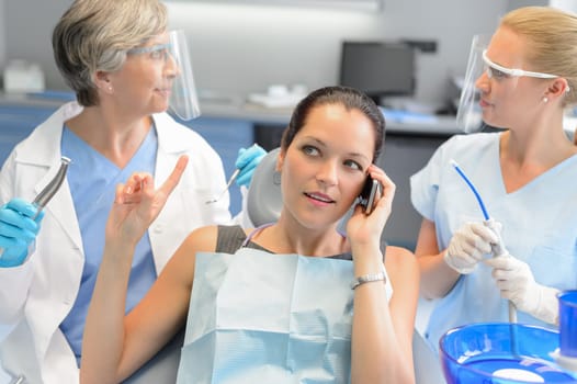 Busy businesswoman at dental surgery calling on phone dentists waiting