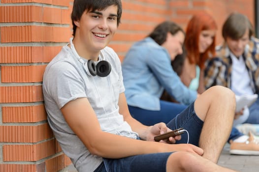 College student boy sitting on ground with friends hanging out