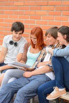 Group of students sitting bench outside college writing notes brainstorming