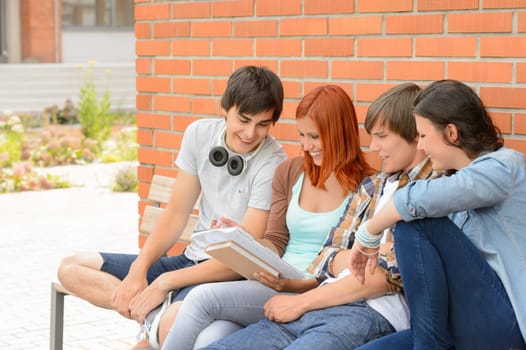 Student friends studying together sitting outside college campus discussing notes