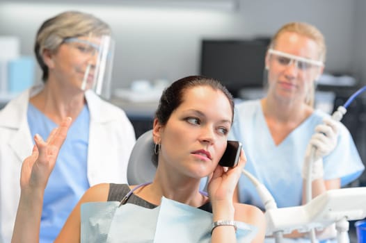Impolite businesswoman on phone in dental office letting dentist wait