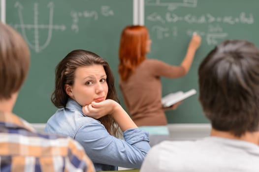 Bored student girl during math lesson sitting front of chalkboard