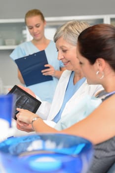 Woman patient at dental surgery point teeth xray tablet dentist