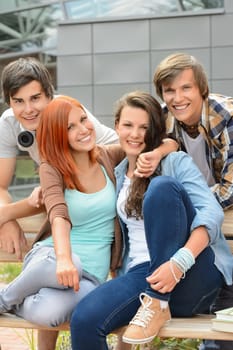 Cheerful group of high school friends hanging out outside campus