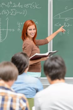 Mathematics student girl pointing on chalkboard looking at classmates