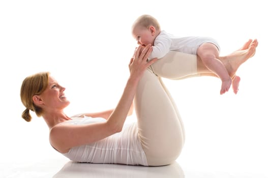 Young mother does back-education gymnastics with her 6-month-old daughter,isolated against a white background. Mum lies on the ground and has her baby lying on her back.