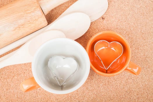 Ceramic cups with cookies cutter on cooking table