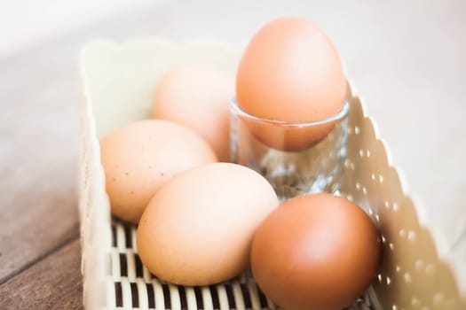 Chicken eggs in a basket on wooden table