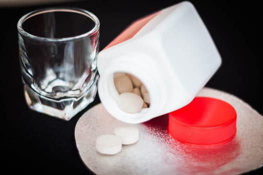 Open pill bottle with brown medicine spilling out