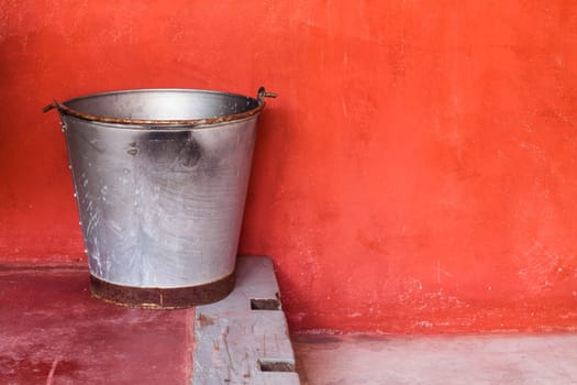 Small aluminum tank on step against red grunge wall