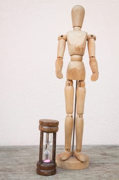 Wood mannequin and hourglass to represent time over