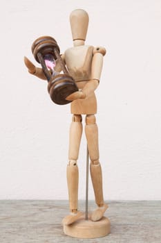 Wood mannequin and hourglass to represent time caring