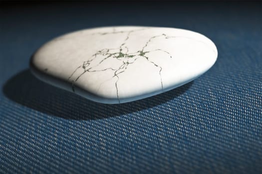 An image of a white pebble on a blue jeans