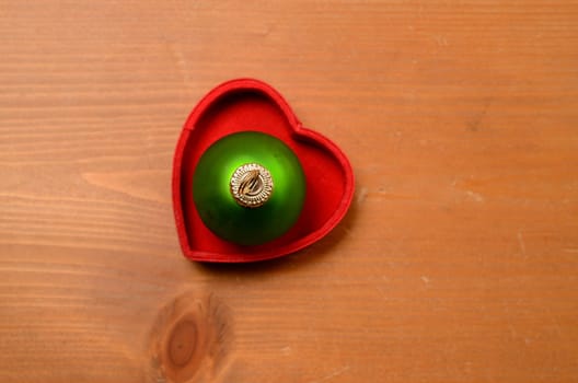 Green old Christmas bauble in a red heart shaped box