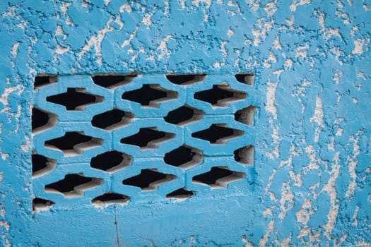 Blue aged street wall with black brick holes