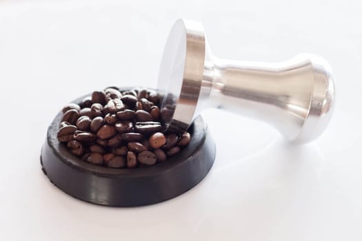 Coffee tamper and roasted coffee in rubber saucer
