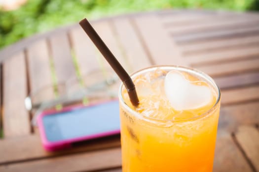 Heart cube ice in fresh orange juice with straw