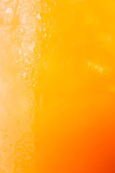 Fizzy glass of iced orange juice up close