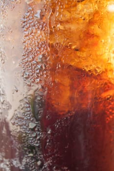 Fizzy cola in a glass with ice cubes
