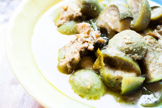 A bowl of spicy green curry with chicken and eggplant