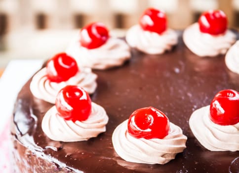 Close up chocolate cake with cherry and whipped cream