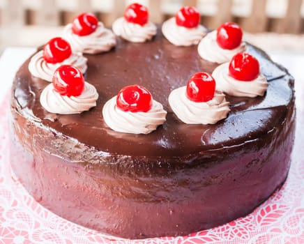 Delicious chocolate cake with red cherry on top