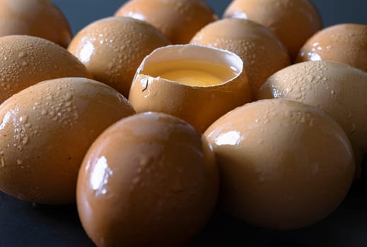 View of Egg yolk in Broken raw chicken eggshell in the among of Fresh chicken egg (Hen egg) on dark background. Natural organic fresh eggs for healthy food, use it as your Space for text, Design, Wallpaper and Poster, Selective focus.