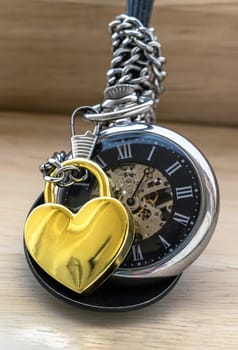 Golden heart shaped love padlock lap over A retro pocket watch on white background. Love can endure beyond the limitations of time, Concept of Love that transcends time, Valentine's day, use it as your Copy space, Design, Wallpaper and Poster, Selective focus.