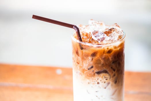 A glass of milk coffee with ice cubes