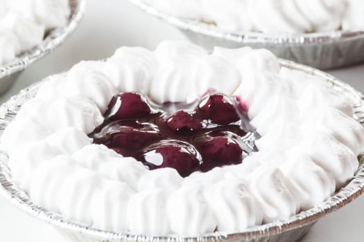 Cupcake of cheesecake topped with blueberries and whipped cream