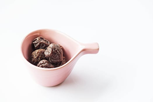 Sweet dried pink plum in ceramic cup