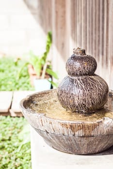 Earthenware garden jar with water spring on sunlight