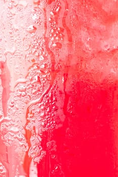 Glass surface of red water with ice cubes background