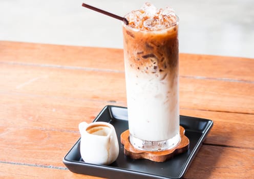 Glass of cold coffee latte with espresso pitcher