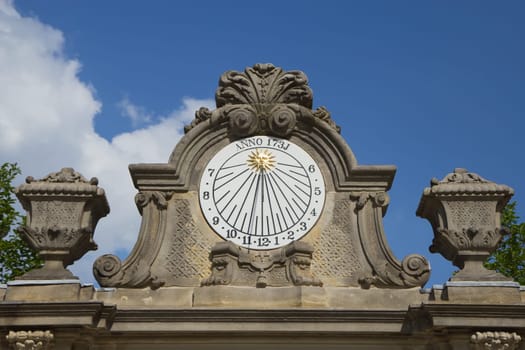 Old stone sundial with blue sky and clouds in the background.