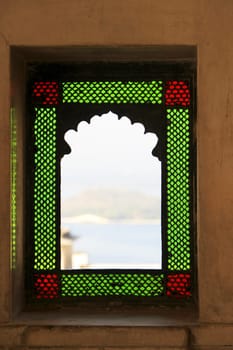 Arched balcony window framed with green and red color glass at City Palace, Udaipur, Rajasthan, India, Asia