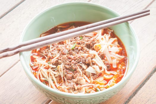 Spicy noodle soup with chopsticks on wood table