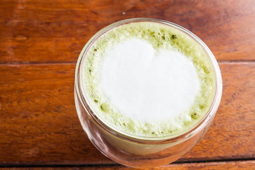 Hot matcha green tea latte on wooden table