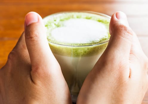 Hands hold hot drink of matcha green tea latte