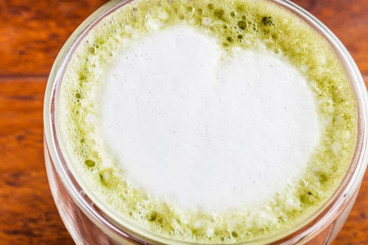 Close up hot matcha green tea latte on wood table