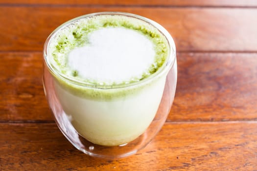 Glass of hot matcha green tea latte with milk microfoam