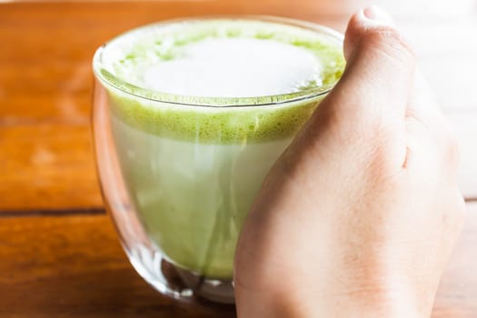 Hand on hot drink of matcha green tea latte