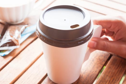 Hot coffee in paper cup serving on wood table