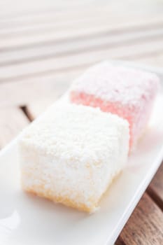Pink and white lamington cakes on wood table, stock photo