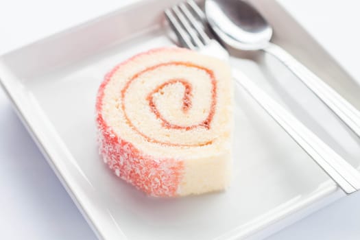 Pink jam roll cake with spoon and fork, stock photo