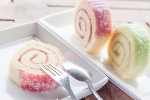 Slice of colorful jam roll on wood table, stock photo